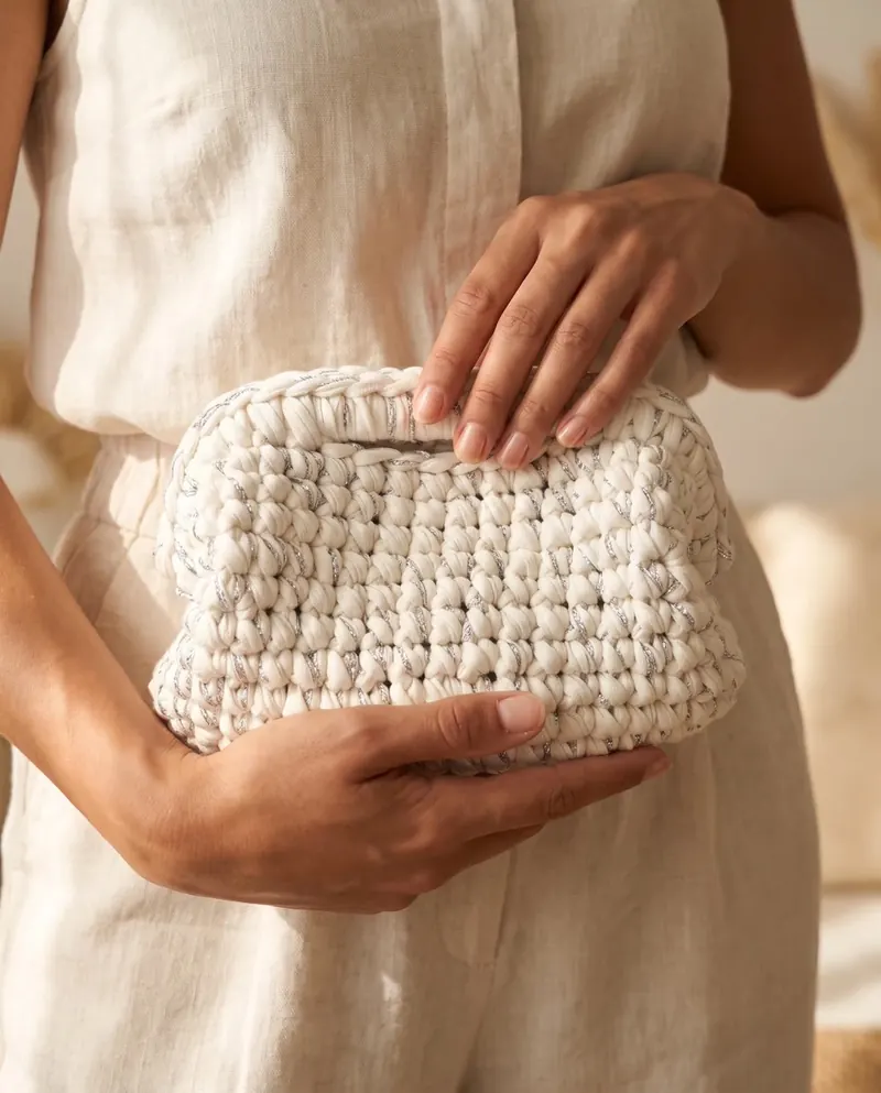 Clutch bianca con filo argento tenuta fra le mani