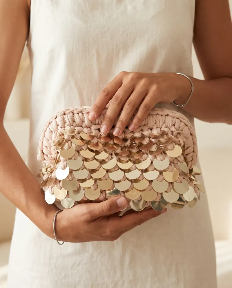 Clutch cipria con paillettes dorate tenuta fra le mani