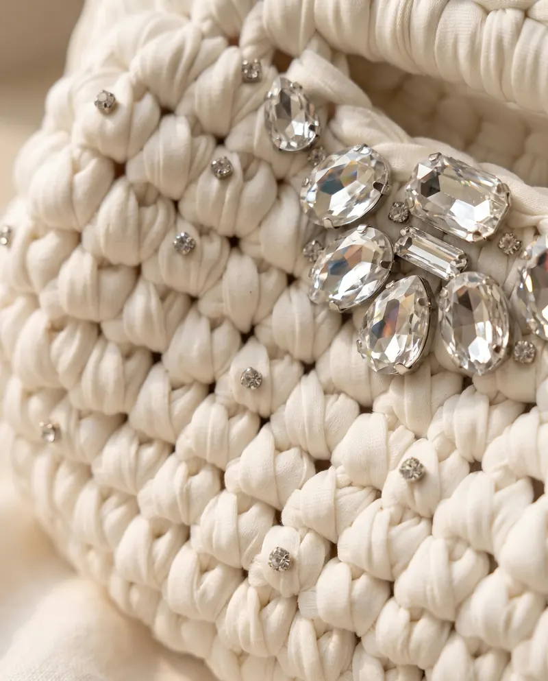 Dettaglio ravvicinato dei cristalli applicati sulla clutch panna